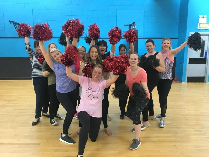 Cheerleading hen party dance class in Bournemouth squad with pom-poms mid-routine